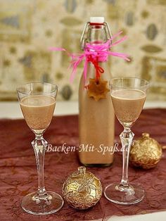 two champagne glasses and an empty bottle on a table with red cloth, gold ornament and pink ribbon