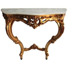 an ornate console table with marble top and gold leaf decoration on the legs, against a white background