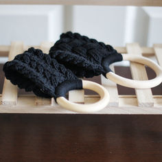 two pairs of black knitted mittens sitting on top of a wooden table next to each other