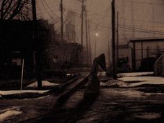 a street with snow on the ground and power lines in the background at night time