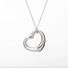 Stylish pre-owned Tiffany & Co Open Heart necklace crafted in sterling silver.    The simple and elegant design by Elsa Peretti celebrates the spirit of love. The Tiffany & Co sterling silver chain measures 16 inches and is great worn alone or layered with your fine jewelry from any era. Also included is a Tiffany & Co travel pouch.   The necklace is in very good original condition and was lightly cleaned and polished.  Particulars:  Weight: 5.6 grams  Stones:  N/A.  Size & Measurements: The necklace measures 16 inches in length. The pendant measures 22mm diameter (0.86 inches).  Metal & Hallmark: Sterling silver. The necklace is hallmarked "Ag 925" and "Tiffany & Co". The pendant is also hallmarked "Tiffany & Co" and "925" for sterling silver and "Spain". Tiffany And Co Silver Necklaces, Chanel Pendant, Purple Pendant Necklace, Art Deco Pendant Necklace, Blue Pendant Necklace, Tiffany And Co Necklace, White Gold Pendant Necklace, Sapphire Necklace Pendants, Open Heart Necklace