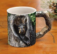 a coffee mug with a bear in a tree trunk on it's side and the image of a bear peeks out from its mouth