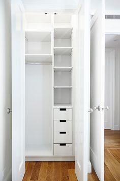 an empty white closet with drawers and shelves