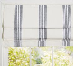 an open window with blue and white striped roman shades on the windowsill in front of it