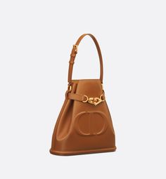 New for Fall 2023, the C'est Dior bag is an elegant and timeless creation. Crafted in golden saddle calfskin, it is distinguished by the embossed CD signature on the front in tribute to the House's savoir-faire. Thanks to its CD Lock closure with a twisting letter D, the bucket bag can keep the essentials secure. A top handle and adjustable, removable chain strap with a leather insert allow the medium bag to be comfortably carried by hand or worn over the shoulder.. Bag Obsession, Medium Bag, Christian Dior Couture, Dior Couture, Letter D, Unique Bags, Boutique Online, Fall 2023, Hermes Bag