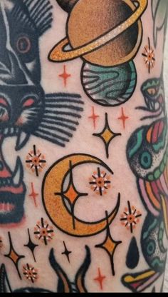 an arm with tattoos on it that include cats, saturn, and the moon in different colors