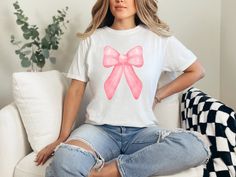 Indulge in the perfect gift for Mom with a trendy coquette pink bow aesthetic on her birthday or for Mother's Day - our Comfort Colors T-shirts.  Crafted from the finest 100% ring-spun USA cotton, these shirts offer unmatched comfort with a medium weight, pre-shrunk fabric.  Our ethically grown and harvested cotton ensures not just a soft touch but also a clear conscience.  The garment-dyed, soft-washed fabric brings an extra layer of coziness to their wardrobe, making these tees an ideal daily choice.  The relaxed fit offers both style and comfort, while the double-needle stitching ensures durability that stands the test of time.  Say goodbye to side-seams as our tubular-shaped shirts maintain their form effortlessly.  Elevate gifting with the perfect blend of quality, style, and personal Trendy Pink Tops For Birthday, Trendy Pink T-shirt For Birthday, Pink Casual T-shirt For Party, Casual Pink Party T-shirt, Casual Pink T-shirt For Party, Cute Pink T-shirt With Bow, Cute Pink Party T-shirt, Cute Party Tops With Bow, Cute Party Tops With Bow Detail