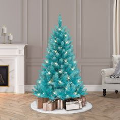 a blue christmas tree in a living room with presents on the floor next to it