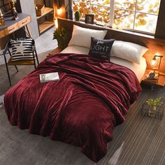 a bed with a red comforter and pillows on top of it in a room