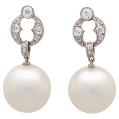 A beautiful pair of vintage Art Deco style pearl and diamond drop earrings set in platinum. Each earring is firstly composed of a circle motif, set throughout with old mine cut diamonds. From this motif hangs a large south sea white pearl which hangs from an articulated bail. They are secured to reverse with a post and butterfly back fitting. Due to the size and design these earrings stand out beautifully on the ear and could be worn for a variety of occasions. There is a total diamond weight of Diamond Cluster Earrings, Earring Stand, Art Deco Stil, Estilo Art Deco, Diamond Star, Art Deco Earrings, Diamond Drop Earrings, Diamond Drops, Art Deco Diamond