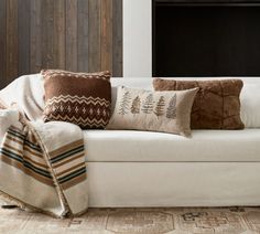 a white couch with pillows and blankets on it in front of a wood paneled wall