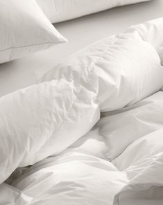 an unmade bed with white pillows and blankets on it's sides, in black and white