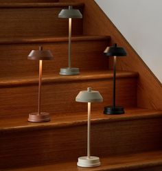 three lamps sitting on top of a set of stairs next to a stair case with wooden steps