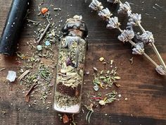 an empty glass bottle filled with herbs on top of a wooden table next to a hammer