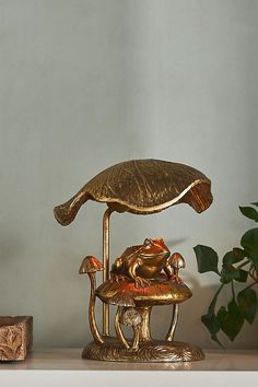 a gold frog statue sitting on top of a table next to a potted plant