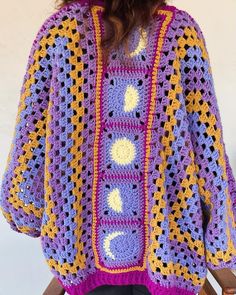 a woman wearing a purple and yellow crocheted sweater with holes in the back