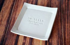 a white square plate with the words 50 years printed on it sitting on a wooden table