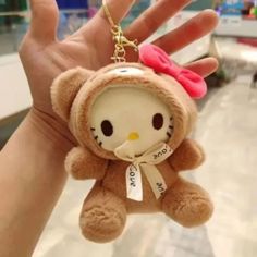 a hello kitty keychain hanging from a person's hand in a mall