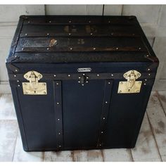 an old black trunk is sitting on the floor