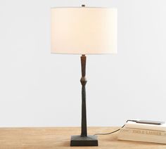 a lamp that is sitting on a table next to a book and a cell phone