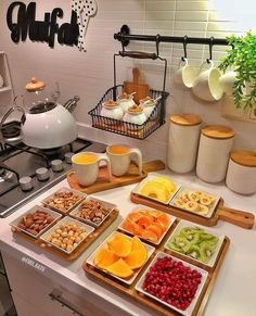 a kitchen counter topped with lots of trays filled with different types of fruits and nuts