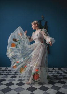 a woman in a long white dress is dancing with her arms spread out and hands outstretched