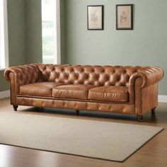 a tan leather couch sitting on top of a hard wood floor next to a white rug