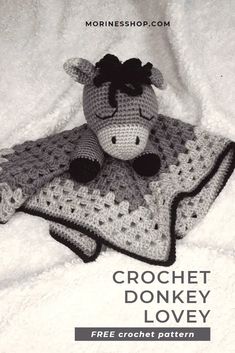 a crocheted cow laying on top of a blanket with the words crochet donkey lovey written below it