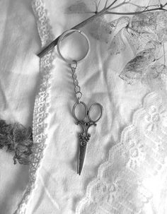 a pair of scissors is hanging from a keychain on a lace tablecloth