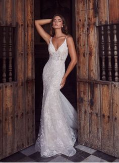 a woman in a white wedding dress standing by an open door with her hand on her head