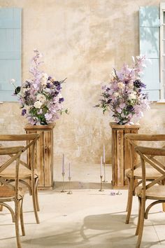 two wooden vases with flowers on them sitting in front of a wall and windows