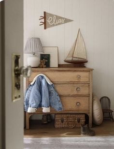 an old dresser with clothes and a sailboat on it