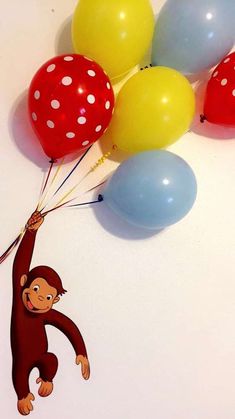 a monkey holding onto some balloons on top of a table