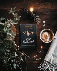 a book sitting on top of a wooden table next to a cup of hot chocolate