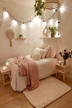 a bedroom with white walls and wooden flooring, lights strung from the ceiling above the bed