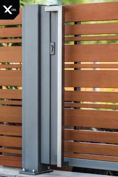 a tall metal door sitting next to a wooden fence with slats on the sides