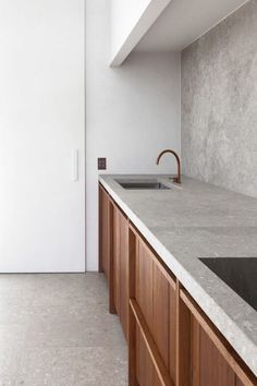 a kitchen counter top sitting under a window next to a sink and cupboards in a room