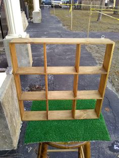 a wooden shelf sitting on top of a grass covered stepladd in front of a building