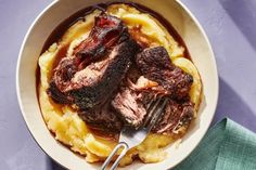 a bowl filled with meat and mashed potatoes on top of a purple table cloth