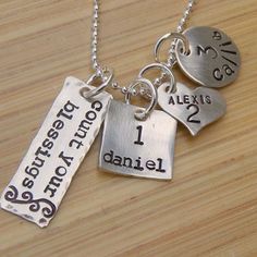 three personalized necklaces with names on them sitting on top of a wooden table