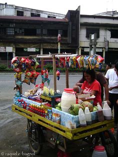 a woman standing next to a cart filled with food