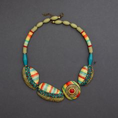 a multicolored necklace is displayed on a gray surface