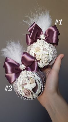 there are two cakes with flowers and feathers on top of each other, one being held in the air by someone's hand