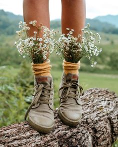 a pair of boots with flowers tied to them on top of a tree stump in the woods