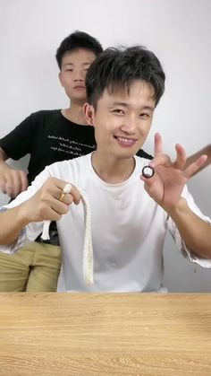 two young men standing next to each other at a table