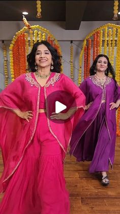 two women in pink and purple outfits are dancing on the dance floor with beads hanging from the ceiling