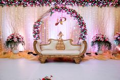 a white couch sitting in front of a flower covered stage with pink and red flowers