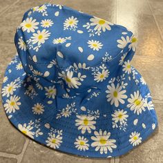 a blue hat with white daisies on it sitting on a tile floor next to a tiled floor