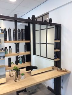 a mirror sitting on top of a wooden table next to a shelf filled with bottles