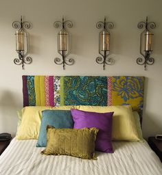 a bed topped with lots of pillows next to two wall sconces on either side of it